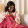 A woman on a couch snuggled into a Custom Map Blanket featuring a bold red map design.