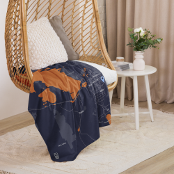 Custom Map Blanket featuring a dark blue and copper map design, draped over a wicker chair in a cozy living room setting.